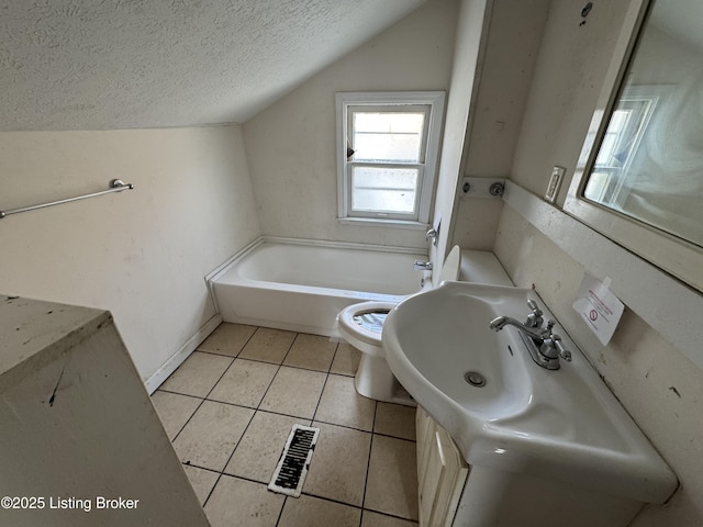 bathroom with vaulted ceiling, tile patterned flooring, toilet, a tub to relax in, and a textured ceiling