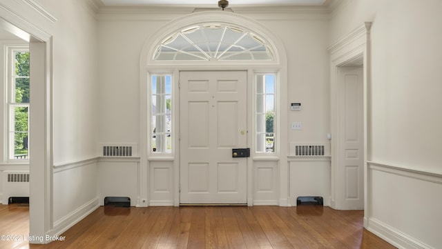 entrance foyer featuring hardwood / wood-style floors, crown molding, and radiator