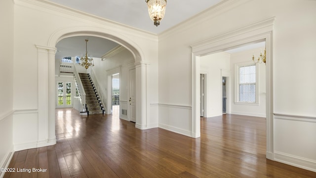 spare room with dark wood-type flooring, a chandelier, and ornamental molding