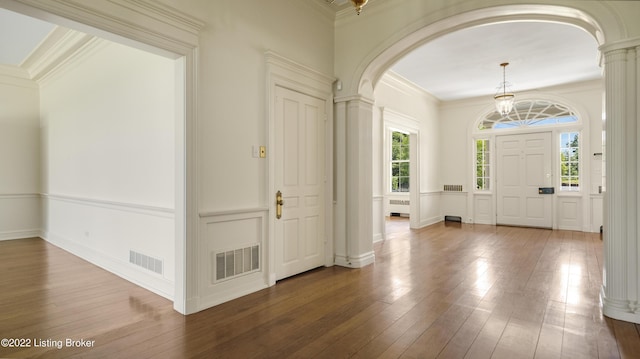 foyer entrance featuring hardwood / wood-style floors, a healthy amount of sunlight, ornate columns, and crown molding