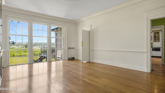 empty room with hardwood / wood-style floors and ornamental molding