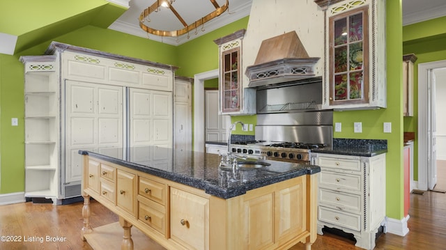 kitchen with a kitchen island with sink, sink, light hardwood / wood-style flooring, light brown cabinetry, and custom range hood