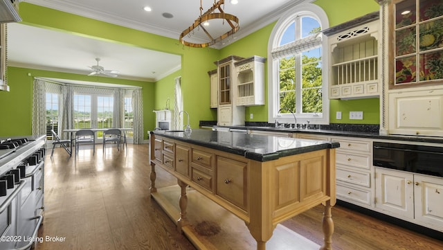 kitchen with ceiling fan, dark wood-type flooring, sink, decorative light fixtures, and a center island with sink