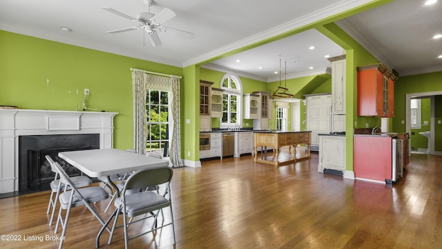 dining space with dark wood-type flooring, ceiling fan, ornamental molding, and sink