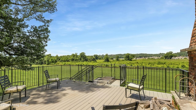 wooden deck featuring a rural view and a yard