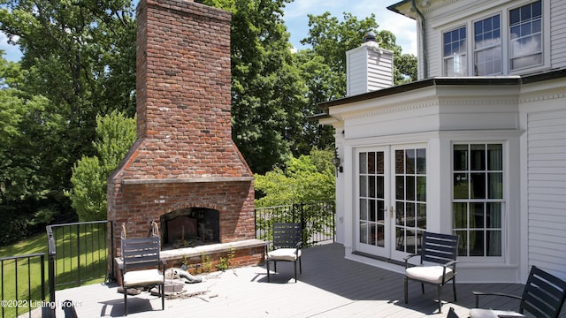 wooden deck featuring an outdoor brick fireplace and french doors