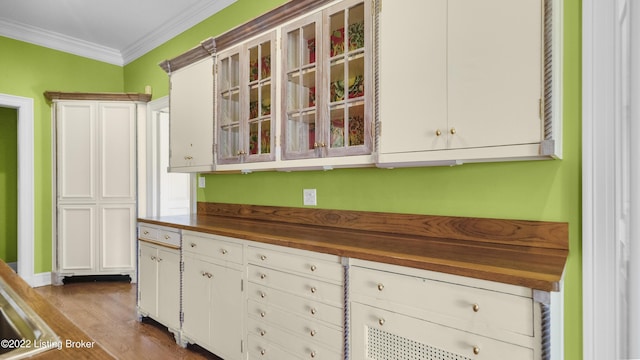 kitchen featuring wooden counters, light hardwood / wood-style floors, white cabinetry, and crown molding