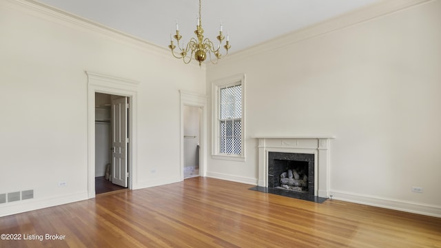 unfurnished living room with a fireplace, wood-type flooring, an inviting chandelier, and crown molding