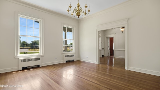 spare room featuring hardwood / wood-style flooring, a notable chandelier, radiator heating unit, and ornamental molding