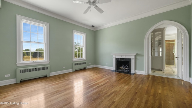 unfurnished living room featuring radiator, ceiling fan, a fireplace, and wood-type flooring