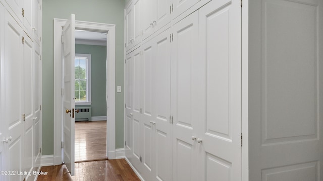 hall with radiator, dark wood-type flooring, and ornamental molding