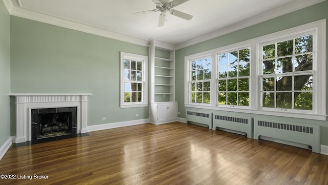 unfurnished living room featuring built in shelves, ceiling fan, radiator, and a premium fireplace