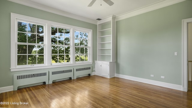 unfurnished room with built in shelves, ceiling fan, radiator heating unit, and hardwood / wood-style floors