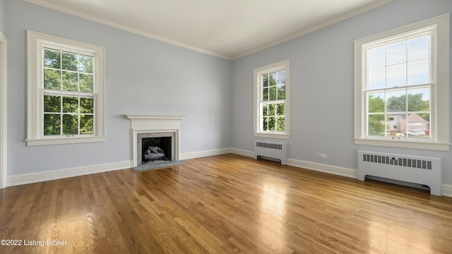 unfurnished living room with radiator heating unit, light hardwood / wood-style floors, and ornamental molding