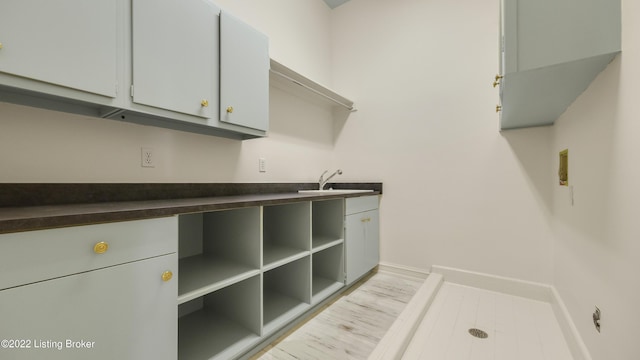 laundry area with cabinets, light hardwood / wood-style floors, and sink