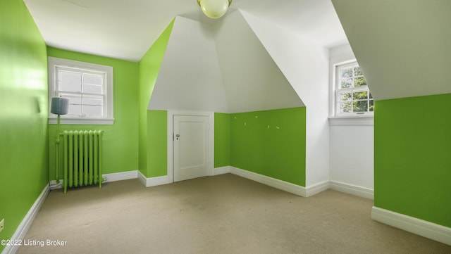 bonus room with radiator heating unit, light carpet, and vaulted ceiling