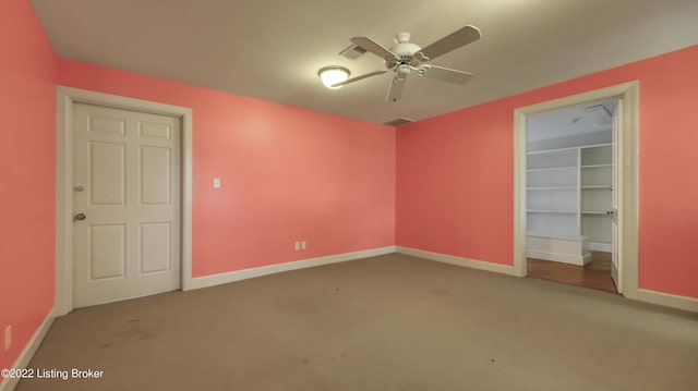 unfurnished bedroom with carpet flooring, a walk in closet, ceiling fan, and a closet