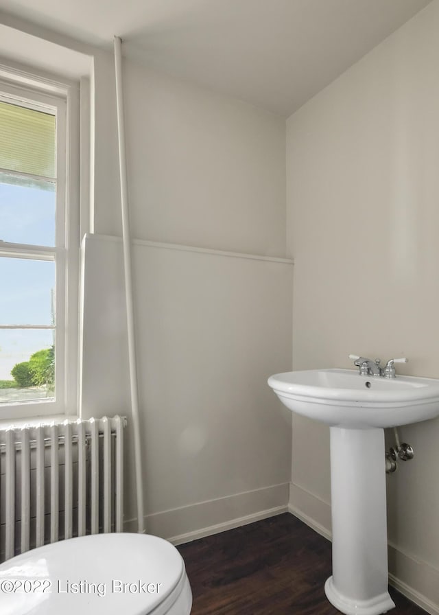 bathroom with radiator heating unit, toilet, and hardwood / wood-style floors