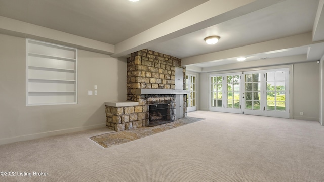 unfurnished living room with a fireplace, built in shelves, and light colored carpet