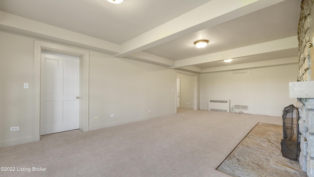 basement with a stone fireplace, light carpet, and radiator