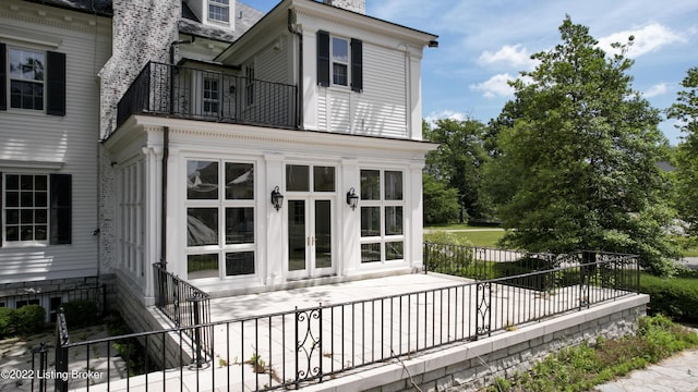 rear view of house featuring a balcony and french doors