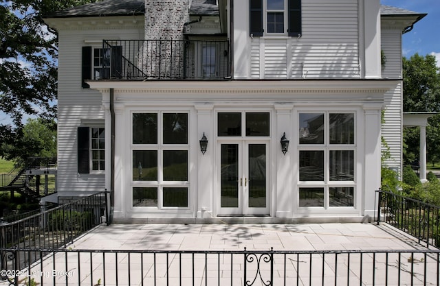 rear view of property with a balcony and french doors