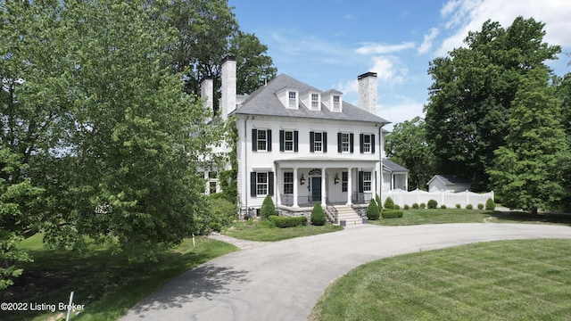 colonial inspired home featuring covered porch and a front yard