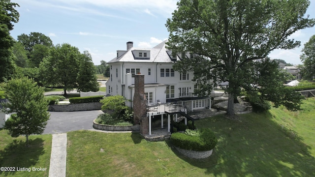 back of house featuring a lawn and a deck