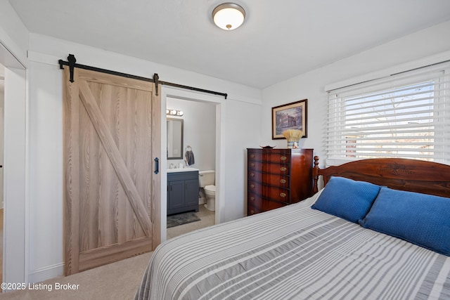 carpeted bedroom featuring connected bathroom and a barn door