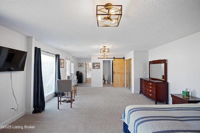 bedroom featuring light carpet, a textured ceiling, and a barn door