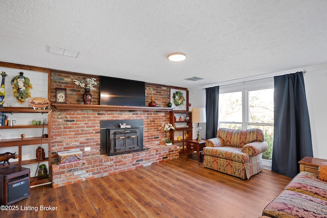 living room featuring a wood stove, a textured ceiling, and hardwood / wood-style flooring