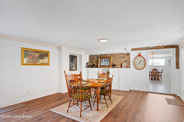 dining room featuring hardwood / wood-style floors, brick wall, and ornamental molding