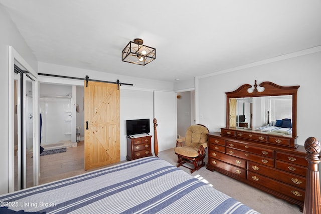 bedroom featuring a barn door, light colored carpet, ensuite bath, and a closet