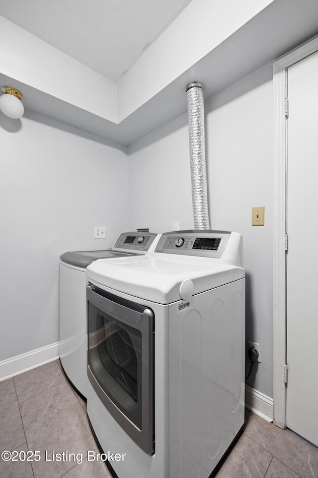 clothes washing area featuring washing machine and clothes dryer and light tile patterned floors