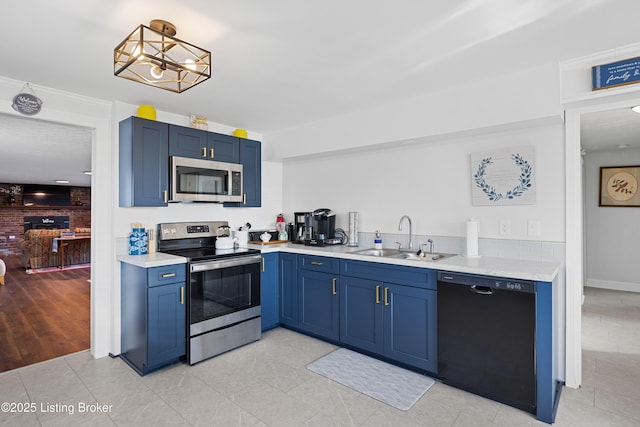 kitchen with pendant lighting, blue cabinets, sink, light tile patterned floors, and stainless steel appliances