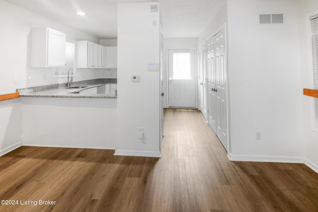 kitchen with white cabinets, dark hardwood / wood-style floors, light stone countertops, and sink