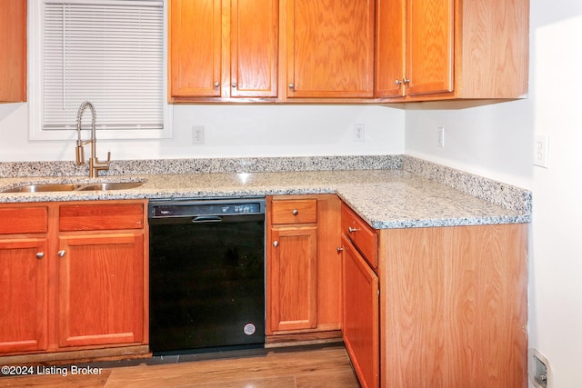 kitchen with light stone countertops, sink, light hardwood / wood-style flooring, and black dishwasher