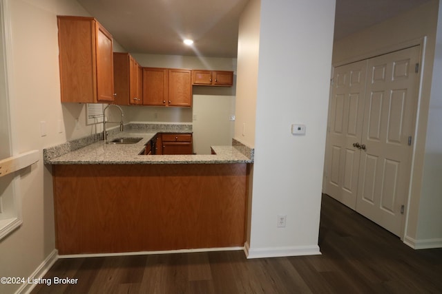 kitchen with light stone countertops, sink, and dark hardwood / wood-style floors