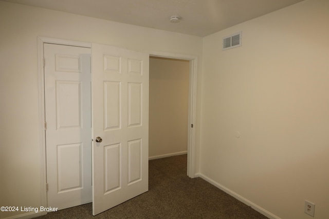 unfurnished bedroom with a closet and dark carpet