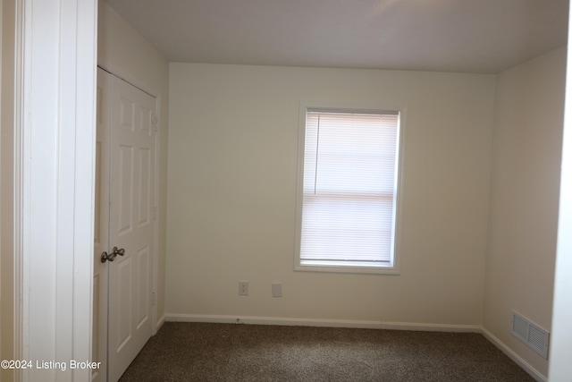 spare room featuring dark colored carpet