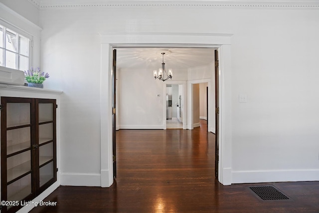 hallway with dark hardwood / wood-style floors and a chandelier