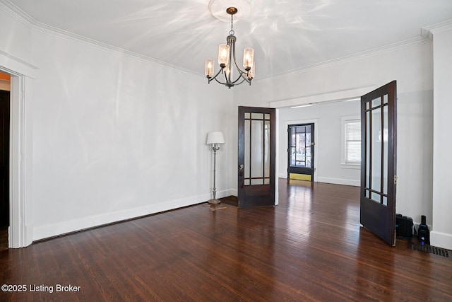 empty room featuring crown molding, dark hardwood / wood-style floors, an inviting chandelier, and french doors