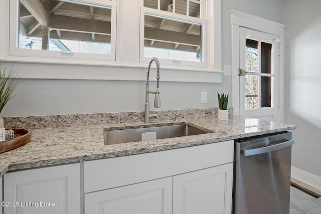 kitchen with white cabinetry, sink, stainless steel dishwasher, and light stone countertops