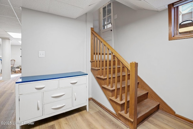 stairway featuring a paneled ceiling and hardwood / wood-style floors