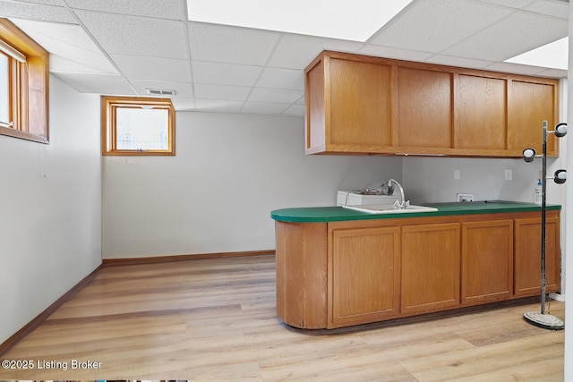 kitchen with sink, a drop ceiling, and light wood-type flooring