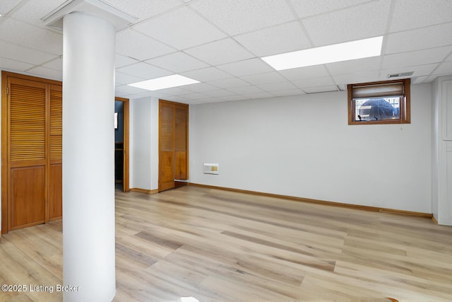 basement featuring a paneled ceiling and light hardwood / wood-style floors