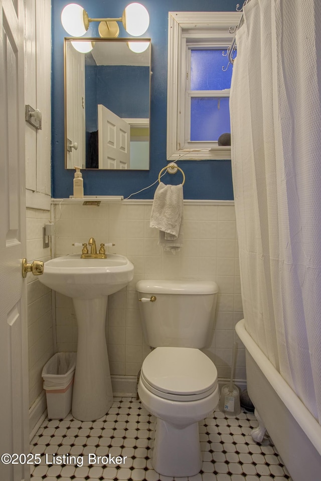 bathroom with toilet, tile walls, and tile patterned floors