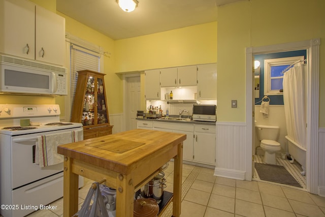 kitchen with light tile patterned flooring, sink, white cabinets, and white appliances