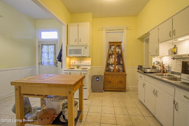 kitchen with white cabinetry, white appliances, and light tile patterned floors