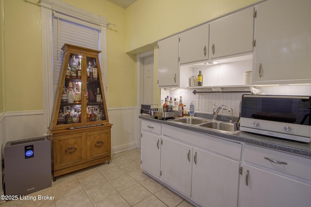 kitchen with light tile patterned floors, sink, and white cabinets